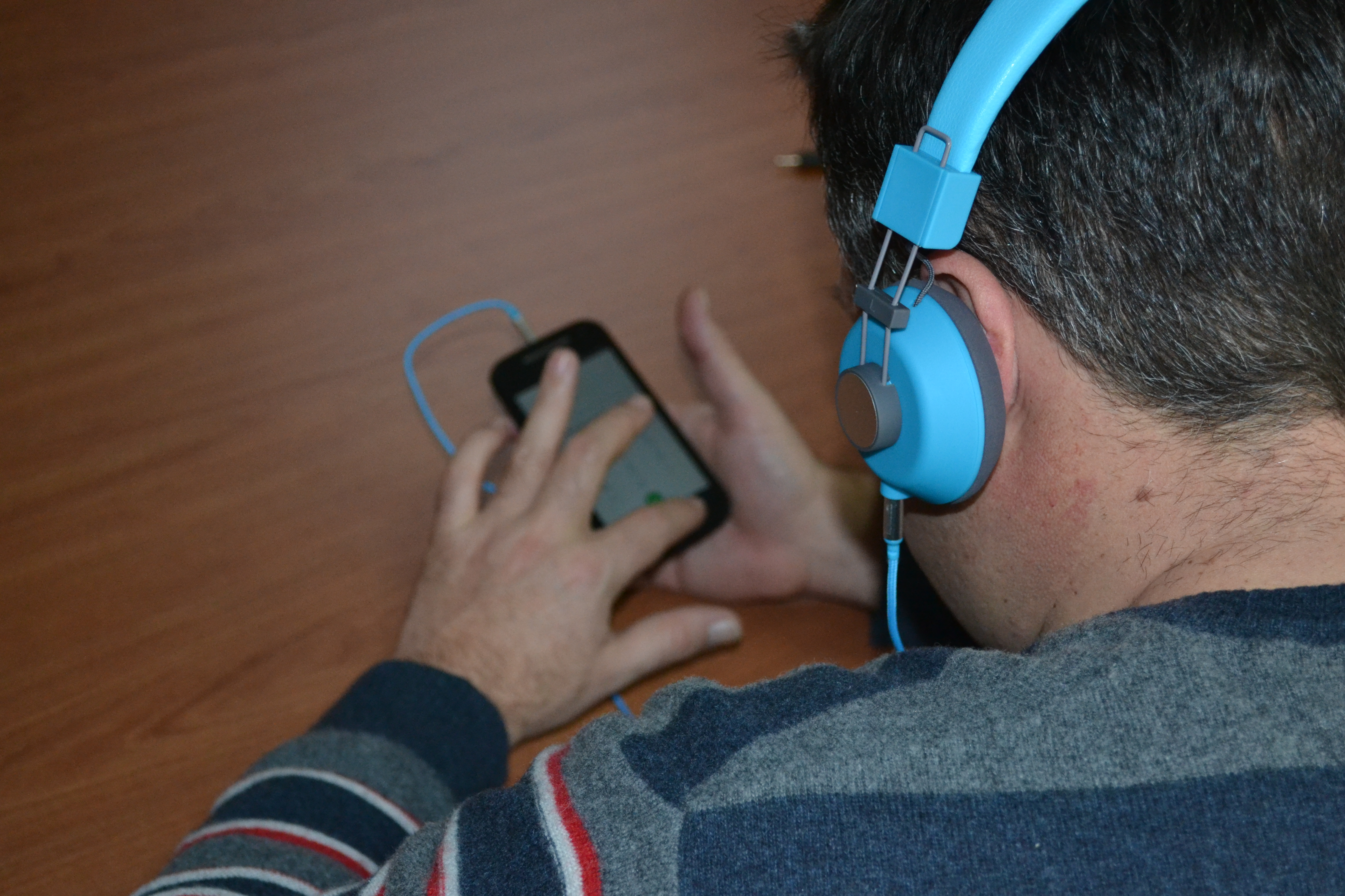A blind person using an headset and exploring a smartphone touchscreen with explore by touch.