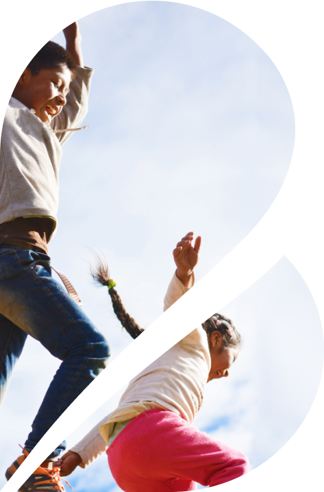 A low angle image of two children lauging while jumping off of an unseen platform.