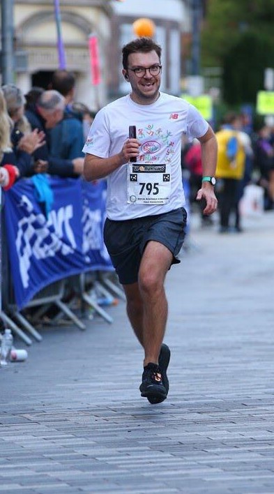 Colin sprinting at finish line at the end of a half marathon with grimace on face