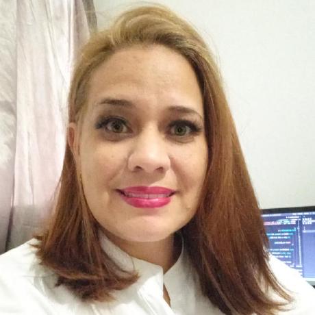 Foto de Maoly Lara, se identifica como ela/dela, é uma menina branca, com cabelo solto rubio, camisa branca, com um fundo cinza claro